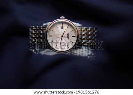 elegant gold watch on a navy blue background. Prestigious businessman watch on the background of a suit. Luxurious wrist watch with date.