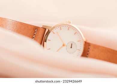 Elegant gold women wristwatch with gold case and leather strap isolated over white background. 