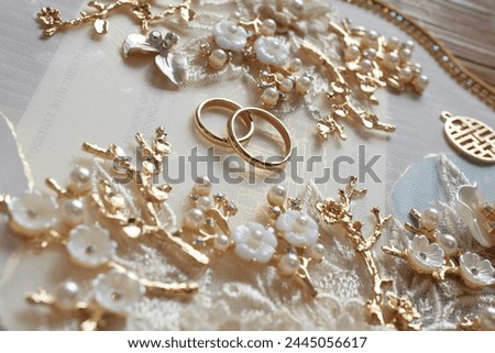 Elegant golden wedding rings surrounded by pearl and gold decor