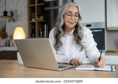 Elegant good-looking senior woman working on laptop - Shutterstock ID 2310471809