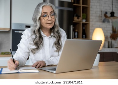 Elegant good-looking senior woman working on laptop - Shutterstock ID 2310471811