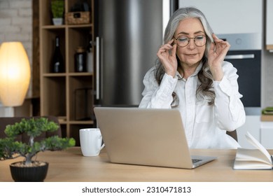 Elegant good-looking senior woman working on laptop - Shutterstock ID 2310471813