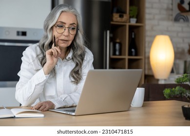 Elegant good-looking senior woman working on laptop - Shutterstock ID 2310471815
