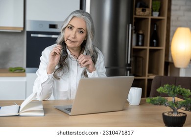 Elegant good-looking senior woman working on laptop - Shutterstock ID 2310471817