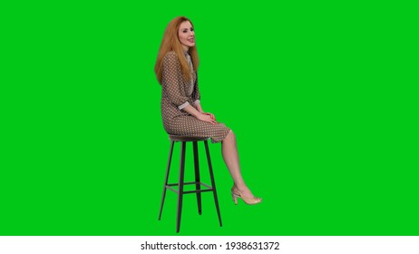 Elegant Graceful Business Woman With Long Hair Sitting On Bar Chair And Telling Story To Audience Against Green Screen Background