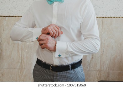 Elegant Groom Buttons The Light Blue Cufflinks On His White Shirt. Tiffany Color Bow Tie. Checkered Grey Suit And A Leather Belt. Wedding Details Photo.