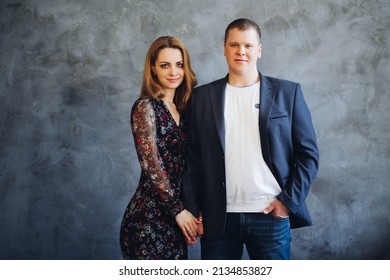 Elegant and happy couple touching each other by hands, posing at camera.