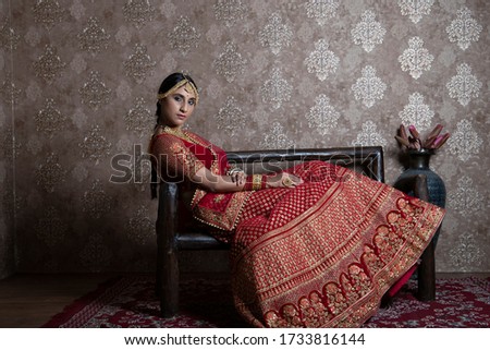 "Elegant Indian Bridal Photoshoot: Stunning Red Lehenga, Vintage Luxury Interior, and Precious Jewellery, a young Indian bride in a resplendent red lehenga