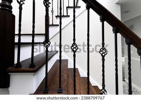 An elegant interior staircase with dark stained wood and white risers, complemented by detailed wrought iron balusters