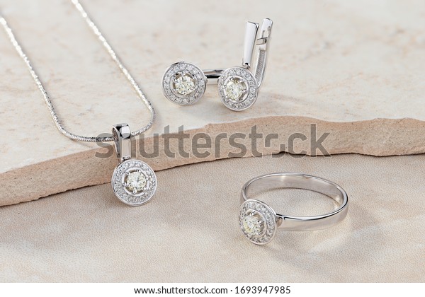 Elegant jewelry set of white gold ring, necklace\
and earrings with diamonds. Silver jewellery set with gemstones.\
Product still life\
concept
