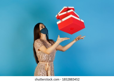 Elegant lady in beige festive dress and protective mask catches a gift boxes thrown in the air. Christmas, New Year, coronavirus concept. - Shutterstock ID 1852883452