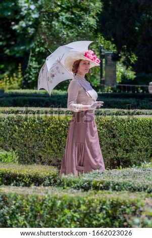 Elegant lady, from high society of the twentieth century, walking through a public park
