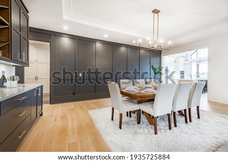 Elegant and large staged dining room with dark cabinets and walls.