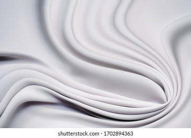 Elegant Light Gray Fabric Backgrounds. Metallic Grey Color Of Shiny Textile, Soft Silver Texture. Satin Folds, Waves Pattern. Luxury Fashion. Smooth Glossy Clothes. Silk Bedsheet.