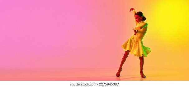 Elegant little girl in adorable stage outfit  dress dancing ballroom dance over gradient pink  yellow background in neon light  Concept beauty  professional dances  skills  Banner and copyspace