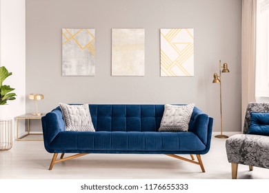 Elegant Living Room Interior With A Comfortable Big Blue Velvet Sofa And Gold Decorations. Real Photo.