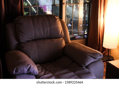 Elegant Living Room Interior With A Lazy Boy Chair And Warm Lighting With A French Window In The Background. Modern Chair Close Up