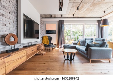 Elegant Living Room With Light Wooden Floor, Grey Couch And Wing Back Chair And Big Tv On The Wall