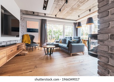 Elegant Living Room With Light Wooden Floor, Grey Couch And Wing Back Chair And Big Tv On The Wall