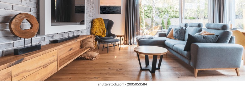 Elegant Living Room With Light Wooden Floor, Grey Couch And Wing Back Chair And Big Tv On The Wall