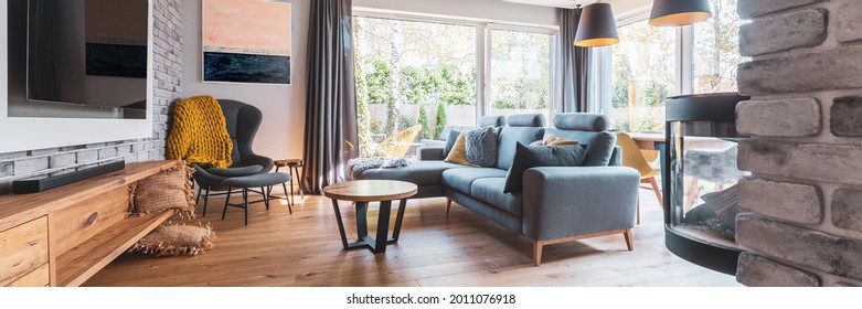 Elegant Living Room With Light Wooden Floor, Grey Couch And Wing Back Chair And Big Tv On The Wall