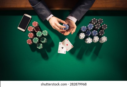 Elegant Male Poker Player With Smartphone Holding Chips, He Has Two Ace Cards, Hands Close Up Top View