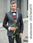 elegant man in black tux. man wearing tux bowtie outdoor. elegant tux man with red rose