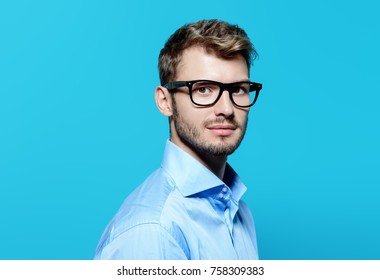 Elegant Man In Glasses Over Blue Background. Optics Style For Men. Handsome Businessman In Spectacles. Male Beauty, Fashion. 