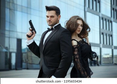 An elegant man with pistols in his hands protects a beautiful girl.