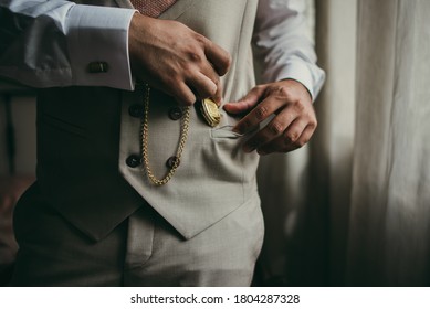 Elegant man with suit. Closeup groom hands holding a pocket watch.