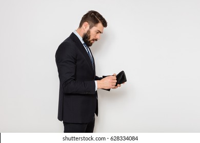 elegant man in suit standing and checking his empty wallet, on white background