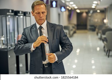 Elegant Man In Suit And Tie Is Leaving Lounge Before Departure And Putting Cel Phone Into Pocket