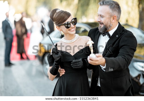 Elegant man and woman\
as a famous movie actors walking together and having fun during\
awards ceremony\
outdoors
