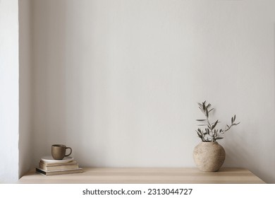 Elegant Mediterranean interior. Vintage vase with olive tree branches, cup of coffee. Books on wooden table. Living room still life. Empty wall copy space. Modern home, apartement design, no people.  - Powered by Shutterstock