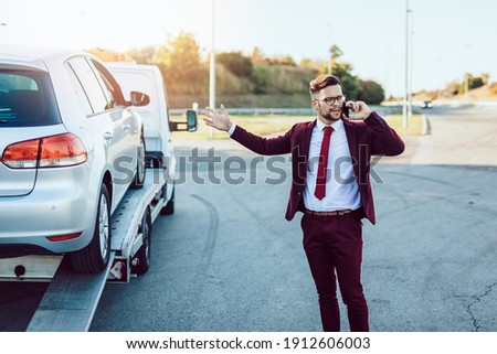 Elegant middle age business man calling towing service for help on the road. Roadside assistance concept.