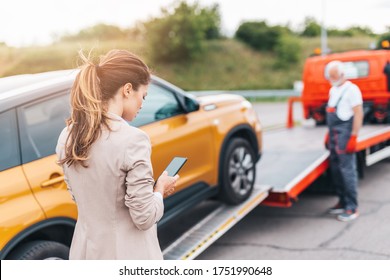 Elegant middle age business woman calling someone while towing service helping her on the road. Roadside assistance concept. - Powered by Shutterstock