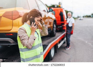 Elegant middle age business woman calling someone while towing service helping her on the road. Roadside assistance concept. - Powered by Shutterstock