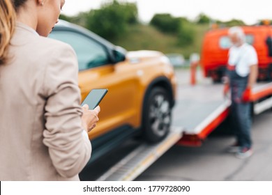 Elegant middle age business woman calling someone while towing service helping her on the road. Roadside assistance concept. - Powered by Shutterstock