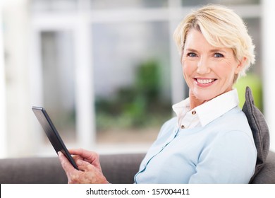 Elegant Middle Aged Woman Using Tablet Pc At Home