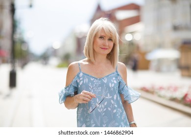 Elegant Middle Aged Woman  Walks Down The Street In Summer Day. Travel Concept