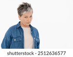 Elegant middle-aged Caucasian woman in casual t-shirt denim jacket in studio setting suspicious uncertain examining you standing isolated on white color background copy space.