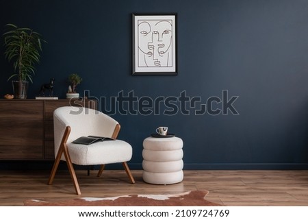 Elegant modern living room interior design with fluffy armchair, pouf, wooden commode, mock up poster frame and modern home accessories. Blue wall. Template. Copy space.