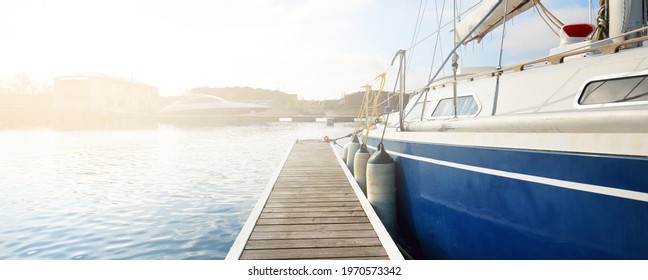 Elegant and modern sailing boats (for rent) moored to a pier in a yacht marina on a clear day. Sweden. Blue sloop rigged yacht close-up. Vacations, sport, amateur recreational sailing, cruise - Powered by Shutterstock