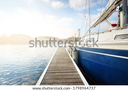 Elegant and modern sailing boats (for rent) moored to a pier in a yacht marina on a clear day. Sweden. Blue sloop rigged yacht close-up. Vacations, sport, amateur recreational sailing, cruise