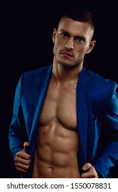 Elegant, muscular, young handsome man posing in fashionable suit on a naked torso, isolated on black background. 