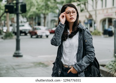 Elegant Office Lady In Glasses Standing On Street Looking Around In City Palo Alto California In Spring. Young Girl Worker Carrying Backpack Going Home From Work. Beautiful Woman Standing On Road.