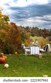 Elegant Outdoor Table Scape With Pumpkins, Cozy Throws And Chairs Against A Dramatic Fall Autumn Folidage