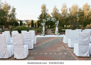 Elegant Outdoor Wedding Setup with Floral Arch and White Chairs. - Powered by Shutterstock