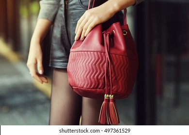 Elegant Outfit. Closeup Of Red Leather Bag In Hands Of Stylish Woman. Fashionable Girl On The Street. Female Fashion. City Lifestyle. Toned