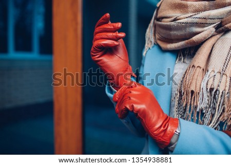 Elegant outfit. Closeup of of stylish woman in coat, scarf and brown gloves. Fashionable girl on the street.